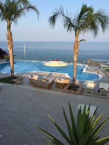 a pool with chairs and an umbrella and palm trees at Marine Park Casa Vacanze in Scifo