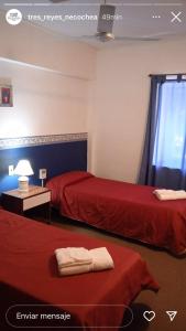 two beds in a room with red sheets at 3Reyes in Necochea