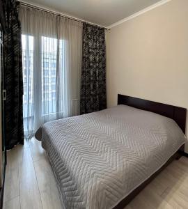 een slaapkamer met een bed en een groot raam bij Апартаменты в ЖК LEGENDA, Алматы (Apartment in LEGENDA Residence) in Alma-Ata