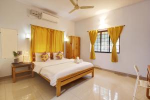 Schlafzimmer mit einem großen Bett und gelben Vorhängen in der Unterkunft Genesis Abode - Cosy 2 BHK Bungalow in Assagao in Mapusa