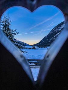 a heart shaped window with a view of a lake at Donneralm in Neustift im Stubaital
