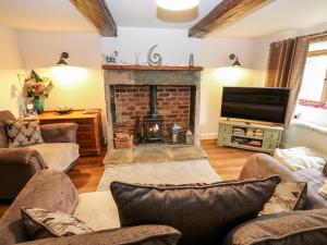 a living room with a fireplace and a tv at Boshaw Cottage in Holmfirth