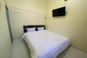 um quarto com uma cama branca e uma televisão na parede em SPOT ON 93452 Wulan Homestay 2 Syariah em Tegal