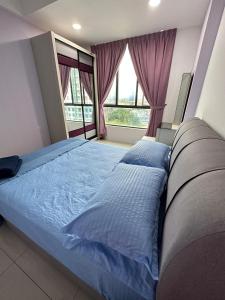 a bedroom with a bed with blue sheets and windows at Eijaz Homestay @ Casa Kayangan in Ipoh