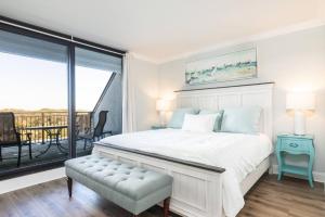 Un dormitorio blanco con una cama y un balcón. en Shipwatch 418 - Luxury Oceanfront Penthouse in Isle of Palms, en Isle of Palms 32 fotos más