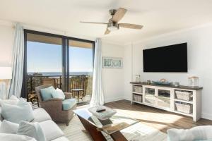 Una sala de estar con un televisor de pantalla plana y un sofá. en Shipwatch 418 - Luxury Oceanfront Penthouse in Isle of Palms, en Isle of Palms