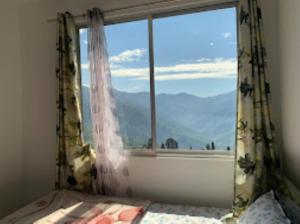 a bedroom with a window with a view of the mountains at The Golden Nest Home Stay , Rongli in Rongli