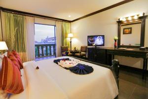 a bedroom with a large white bed and a television at Lucky Angkor Hotel & Spa in Siem Reap
