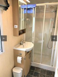 een badkamer met een douche, een wastafel en een toilet bij Vakantiehuis recreatiepark rhederlaagse meren lathum in Lathum