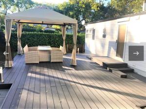 een patio met een tuinhuisje, een tafel en banken bij Vakantiehuis recreatiepark rhederlaagse meren lathum in Lathum