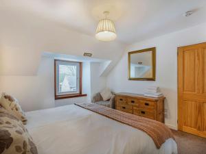 a bedroom with a bed and a dresser and a mirror at 4 Bed in The Cairngorms 46162 in Tomintoul