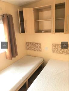 dwa łóżka w małym pokoju z szafkami w obiekcie Vakantiehuis recreatiepark rhederlaagse meren lathum w mieście Lathum