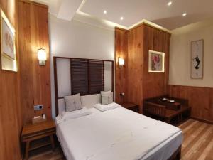 - une chambre avec un grand lit blanc et des murs en bois dans l'établissement 枕窗听雨客栈, à Suzhou