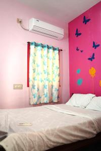 ein Schlafzimmer mit einem Bett und einer rosa Wand mit Schmetterlingen in der Unterkunft pondy Vibes 2bhk home Stay in Puducherry