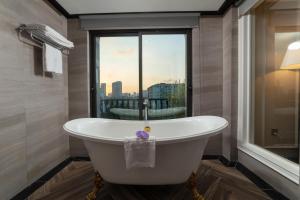 uma banheira num quarto com uma janela em FTE Ba Dinh Hotel em Hanói