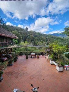 eine Terrasse mit einem Tisch, Stühlen und Bäumen in der Unterkunft Sapa Garden Bungalow in Sa Pa