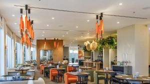 a restaurant with tables and chairs and chandeliers at Almond Hotel - Adults only in Neve Ilan