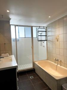 a bathroom with a tub and a shower and a sink at Core beachfront 2 Bedrooms Apartment by Gold Coast Premium in Gold Coast