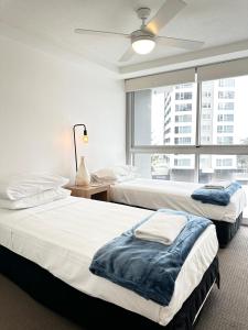 two beds in a room with a large window at Core beachfront 2 Bedrooms Apartment by Gold Coast Premium in Gold Coast