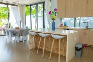 una cocina con una isla con taburetes y una mesa en Beachfront Villa 4 Bedrooms Sanctuary Ho Tram Resort, en Thuận Biên