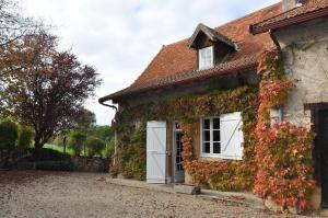Semur-en-Brionnais的住宿－Les Granges De Semur-en-brionnais With Heated Poo，常春藤覆盖的房子,设有白色的门窗