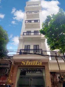 um edifício alto e branco com uma placa à frente. em SHILLA HOTEL em Haiphong