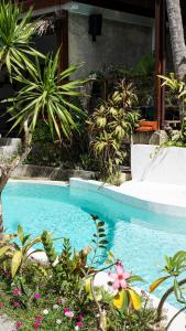 una piscina en un jardín con plantas y flores en Happiness Boutique Resort, en El Nido