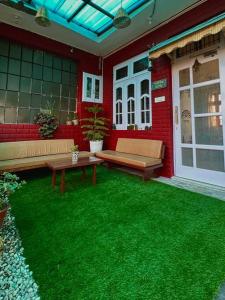een patio met groen gras en banken in een rood huis bij Aikyam Niwas - 1BHK Apartment in Pālampur
