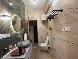 een badkamer met een wastafel, een toilet en een spiegel bij Aikyam Niwas - 1BHK Apartment in Pālampur