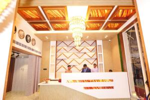 three men standing at a counter in a lobby at 7 Hills Hotel & Resort in Nalanda