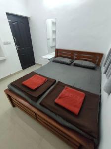 un grande letto con due cuscini rossi sopra di PEARL HUT home stay vythiri Wayanad a Vythiri