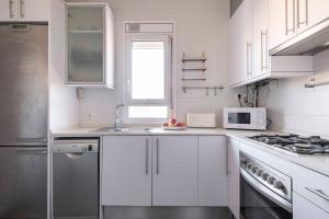 cocina blanca con fregadero y microondas en Sunny Apt Barcelona 22@ en Barcelona