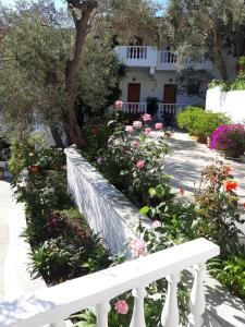 a white bench in front of a garden with flowers at Olive Grove View in Skiathos Town
