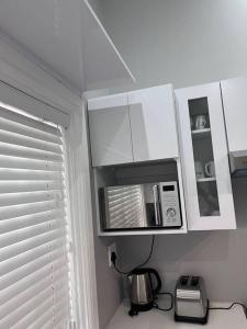 cocina blanca con microondas y ventana en Beverley Grove Guest House en Gqeberha