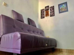 a purple couch in a room with pictures on the wall at Umah De Madya & Rooftop De Madya in Munduk