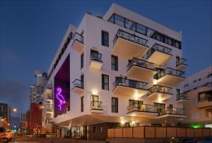 un edificio blanco con un letrero púrpura. en Brown Beach House Tel-Aviv, a member of Brown Hotels, en Tel Aviv