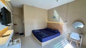 Habitación pequeña con cama azul y TV. en มาชิลล์ รีสอร์ท สังขละบุรี en Sangkhla Buri