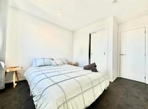 een witte slaapkamer met een groot bed met blauwe kussens bij Immaculate - 2 Bedroom Townhouse close to the train station in Auckland