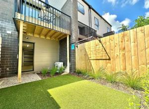 a house with a wooden fence and a yard at Immaculate - 2 Bedroom Townhouse close to the train station in Auckland