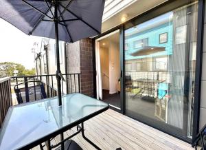 a balcony with a glass table and an umbrella at Immaculate - 2 Bedroom Townhouse close to the train station in Auckland