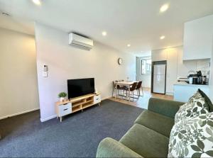 sala de estar con sofá y TV de pantalla plana en Immaculate - 2 Bedroom Townhouse close to the train station en Auckland