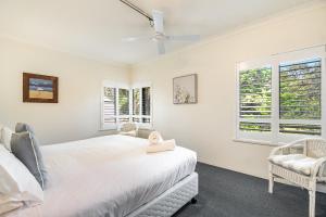a white bedroom with a bed and two windows at Cape Apartments in Byron Bay