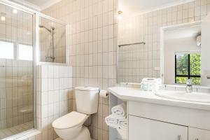 a white bathroom with a toilet and a sink at Cape Apartments in Byron Bay +11 photos