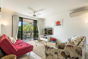 a living room with a red couch and a tv at Cape Apartments in Byron Bay