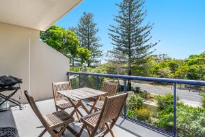 een patio met een tafel en stoelen op een balkon bij Cape Apartments in Byron Bay