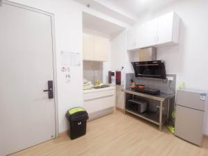 una pequeña cocina con armarios blancos y un cubo de basura en D' Sara Sentral Suites by Manhattan Group, en Sungai Buloh