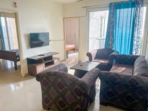 ein Wohnzimmer mit 2 Stühlen, einem Tisch und einem TV in der Unterkunft Friend's Place in Greater Noida