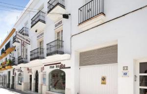 een wit gebouw met balkons in een straat bij Apartamento Pérez Zara 6 in Conil de la Frontera