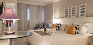 a room with a bed with a table and a lamp at Natal Prime - Porto Imperial in Natal