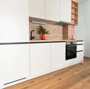 una cocina con armarios blancos y horno negro en Arton Lachtal - Apartments Steiermark, en Lachtal